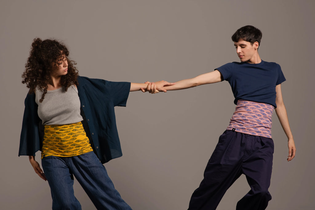 Pareja de bailarines sujetándose de la mano vistiendo haramakis estampados de Happy Belly Barcelona