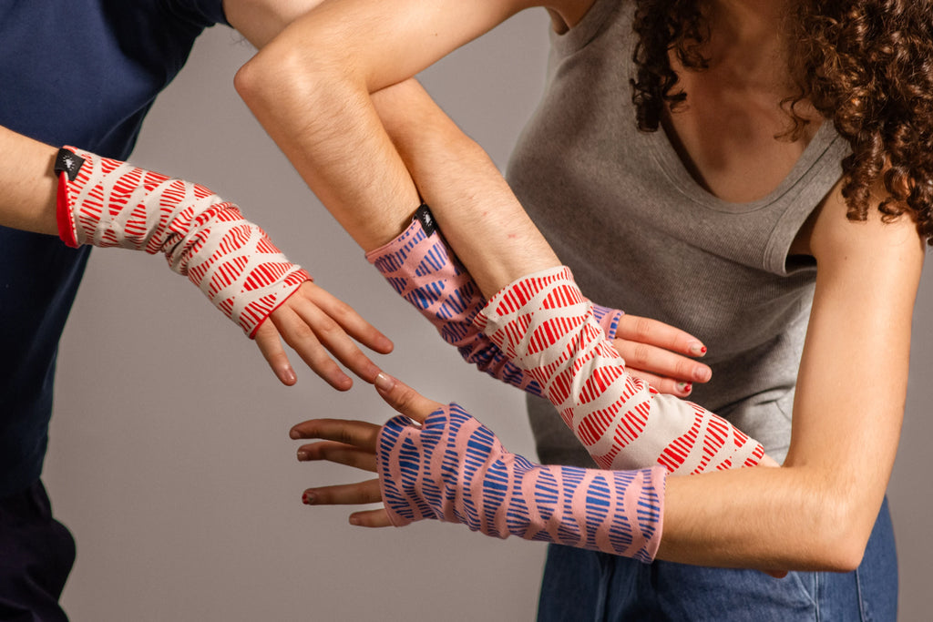 Brazos entrelazados con manos cubiertas por los mitones estampados de Happy Belly Barcelona