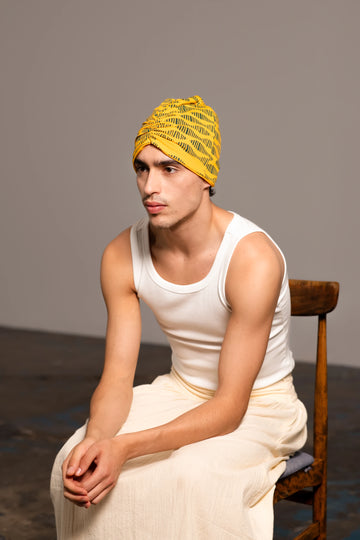 Retrato de medio cuerpo de joven sentado llevando el turbante amarillo estampado de Happy Belly Barcelona