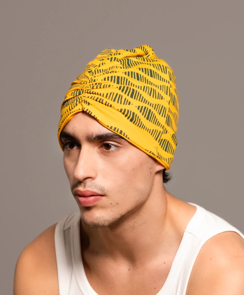 Joven de perfil vistiendo un turbante amarillo y verde de Happy Belly Barcelona