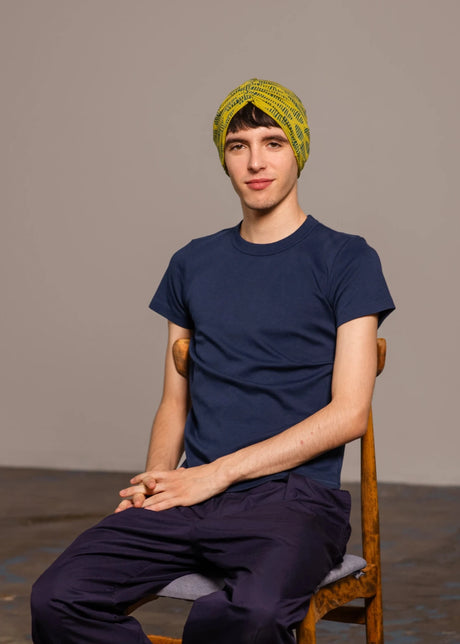 Chico vestido de azul posando sentado con turbante rosa de Happy Belly Barcelona
