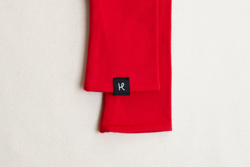 Detalle etiqueta en mitones color rojo de algodón orgánico, marca Happy Belly