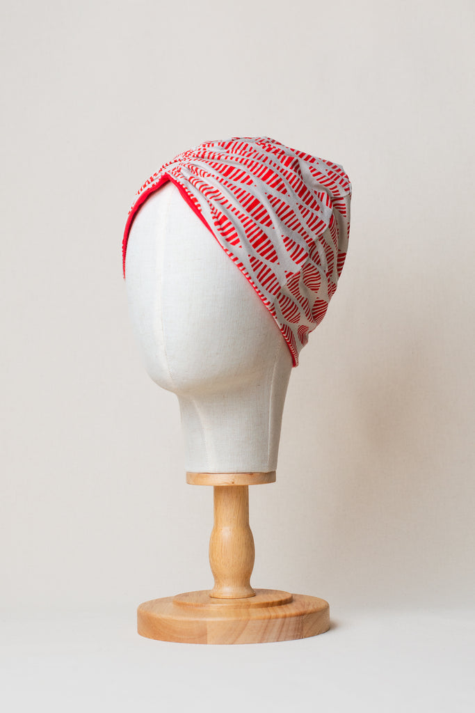 Turbante reversible de algodón orgánico color beige con estampado rojo, detalle de interior color rojo liso