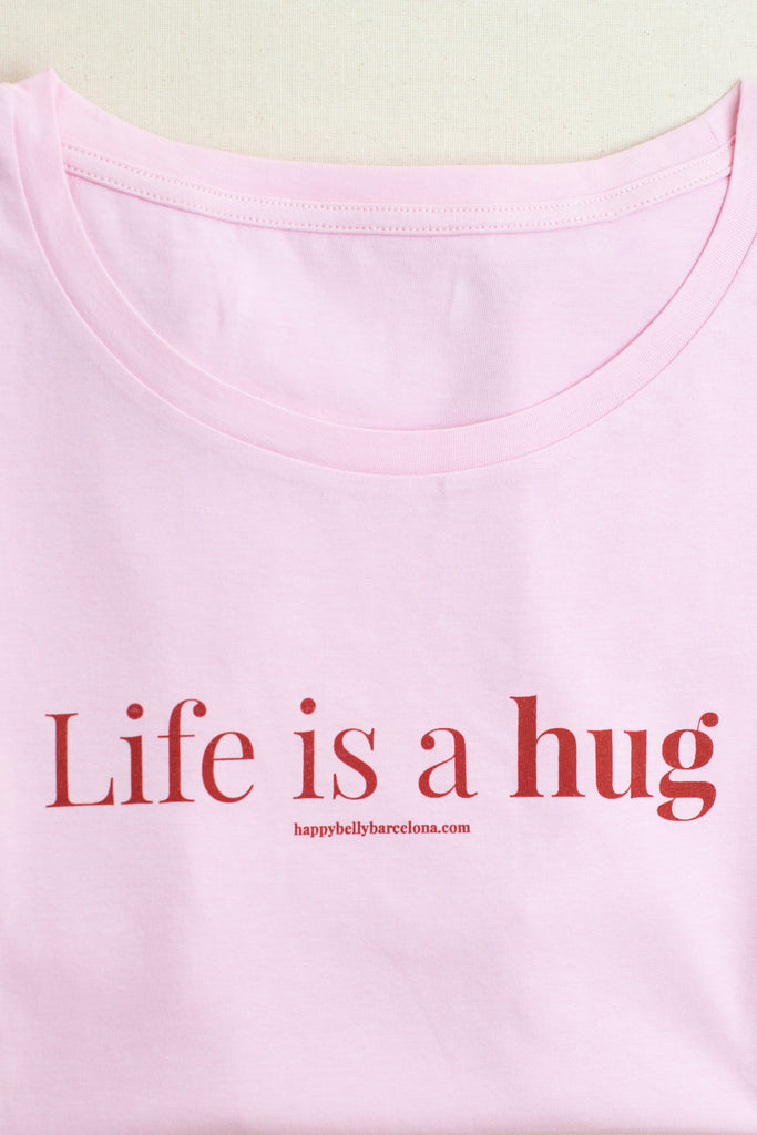 Detalle camiseta algodón orgánico color rosa con lema Life is a hug en rojo