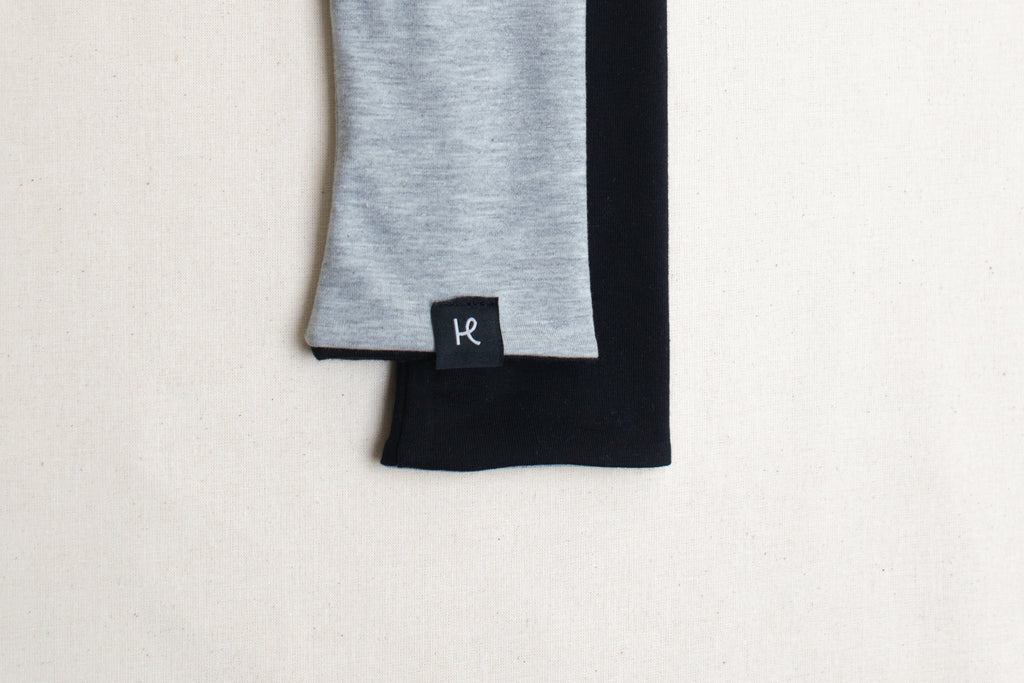 Detalle etiqueta en mitones reversibles color gris y negro de algodón orgánico, marca Happy Belly