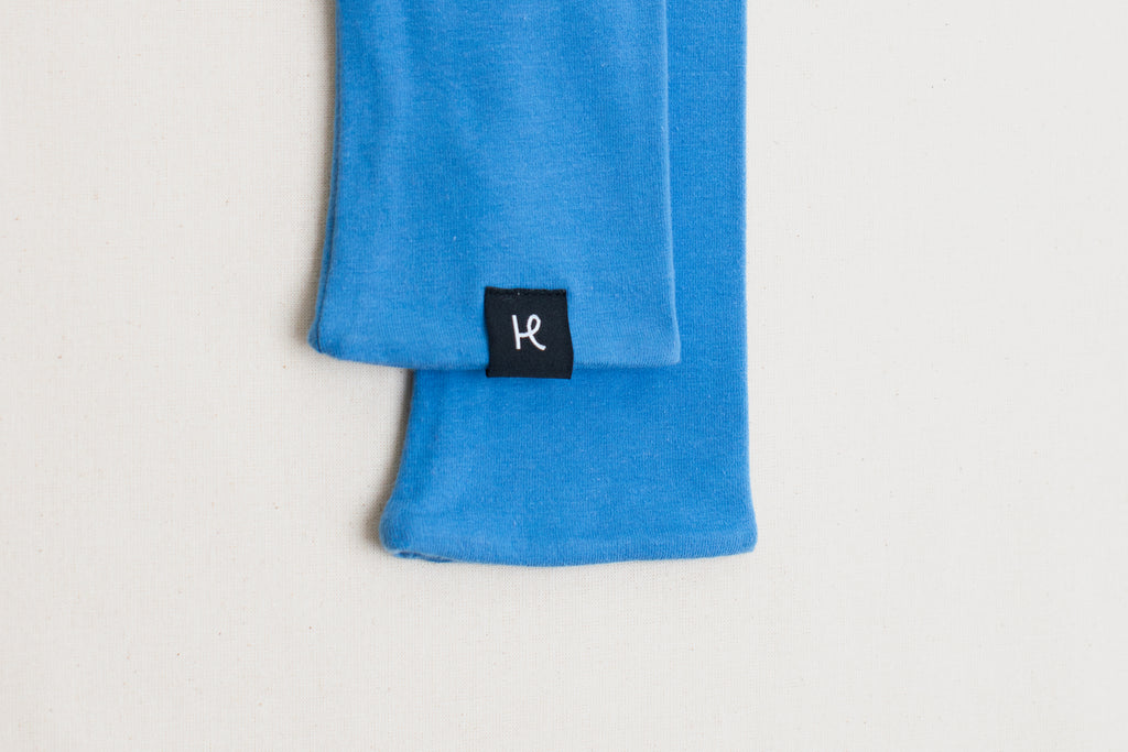 Detalle etiqueta en mitones color azul de algodón orgánico, marca Happy Belly