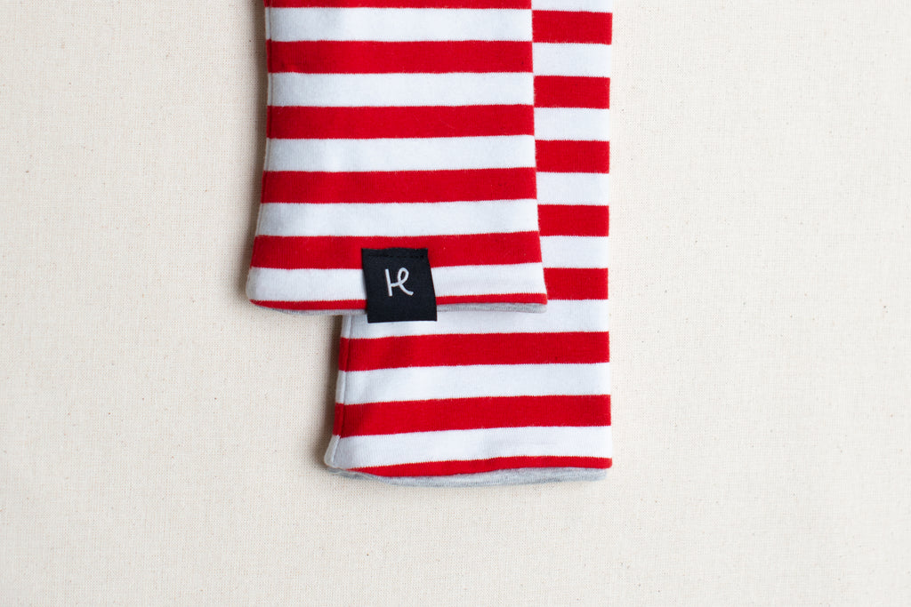 Detalle de etiqueta en mitones reversibles de rayas rojas y blancas, de algodón orgánico, marca Happy Belly