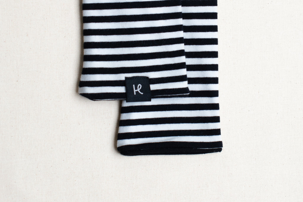Detalle de etiqueta en mitones reversibles de rayas negras y blancas, de algodón orgánico, marca Happy Belly