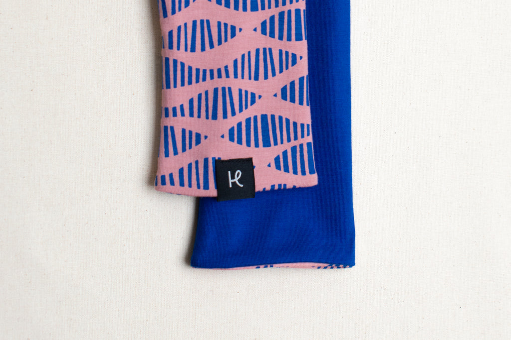 Detalle etiqueta en mitones reversibles rosa y azul eléctrico estampados con serigrafía de la marca Happy Belly