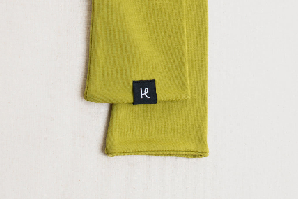 Detalle de etiqueta en mitones verde lima, de algodón orgánico, marca Happy Belly