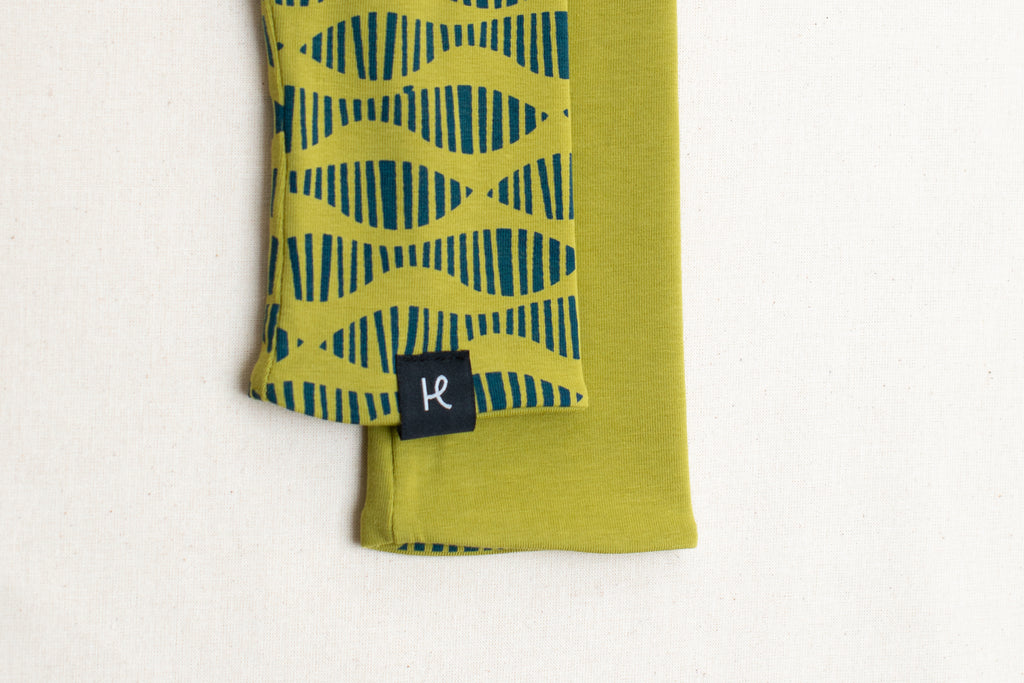 Detalle etiqueta en mitones verde llima estampados con serigrafía de algodón orgánico, marca Happy Belly