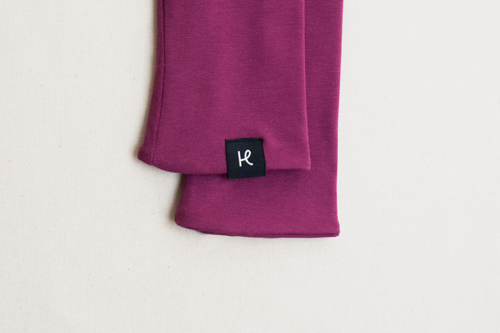 Detalle etiqueta en mitones color morado de algodón orgánico, marca Happy Belly